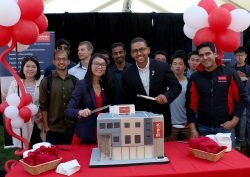 Brock University Goodman School of Business students Leona Yiu and Nick Hollard cut a cake in the shape of the new $22-million expansion and renovation project Friday during a beginning of construction celebration while fellow business students look on.