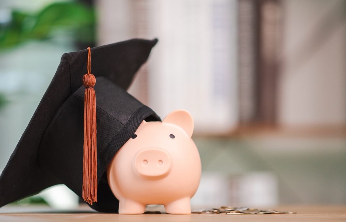 A photograph of a piggy bank with a mortarboard draped across it