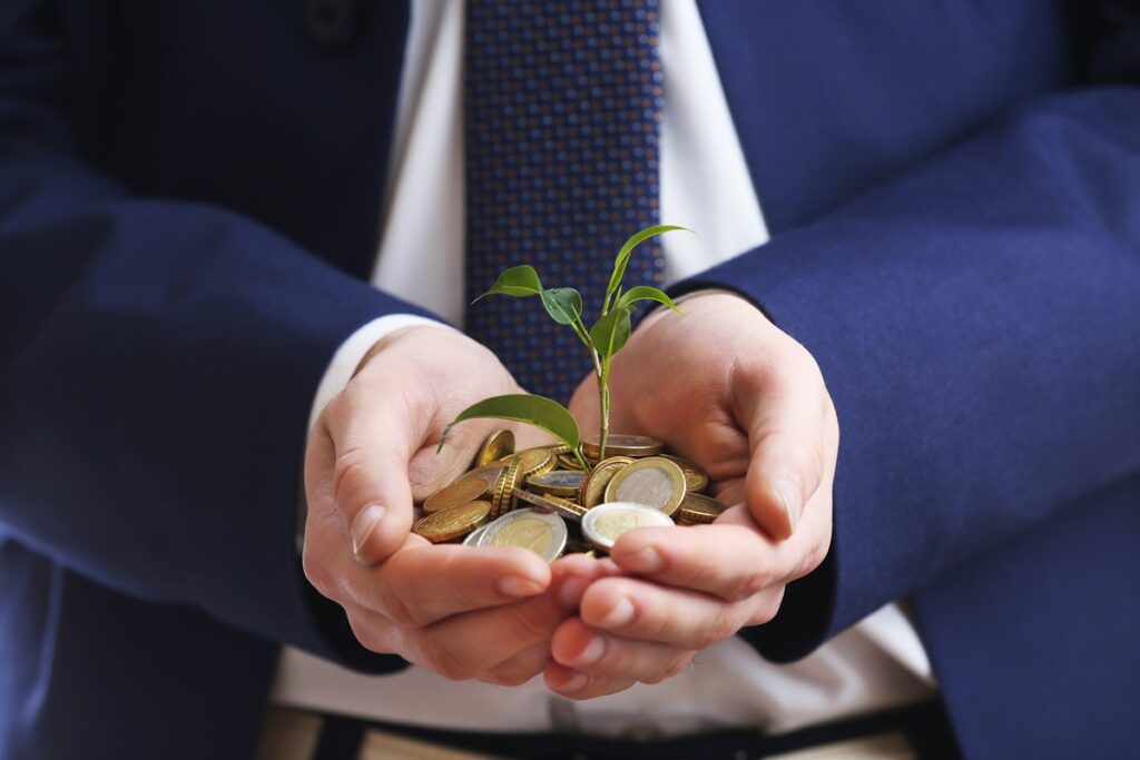 Handful of coins with growing sprout, closeup view