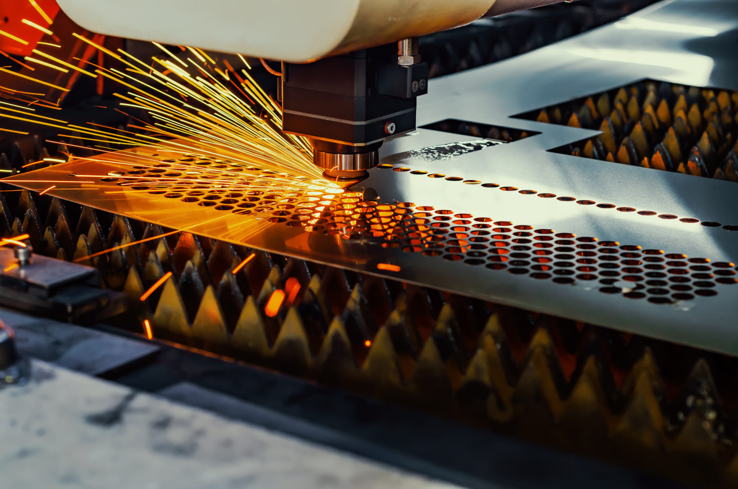 A CNC laser cuts holes in a sheet of metal in a factory