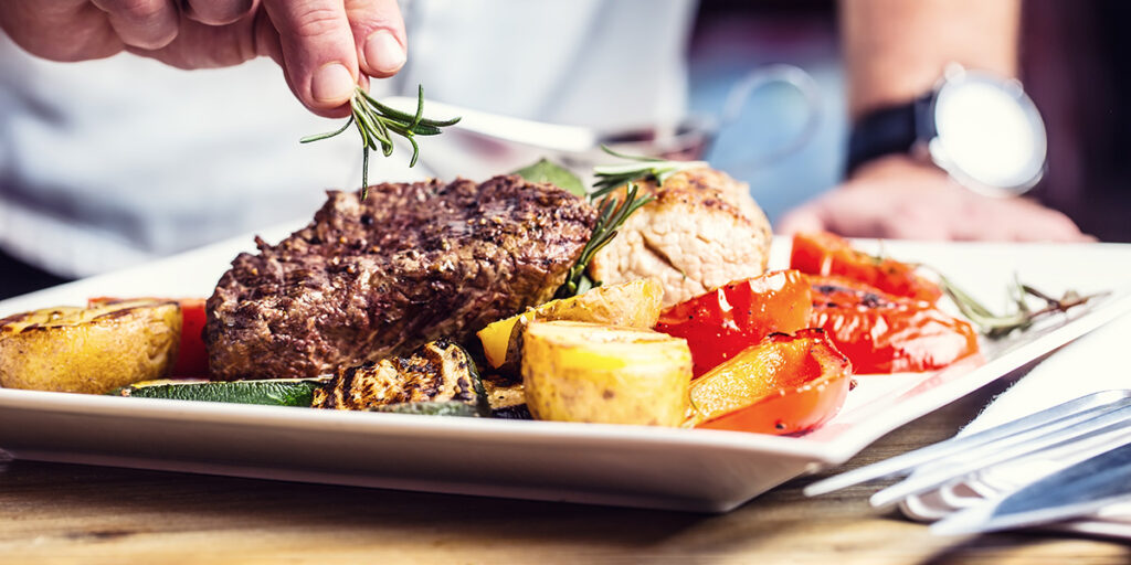 A chef adds a garnish to a dish in a restaurant