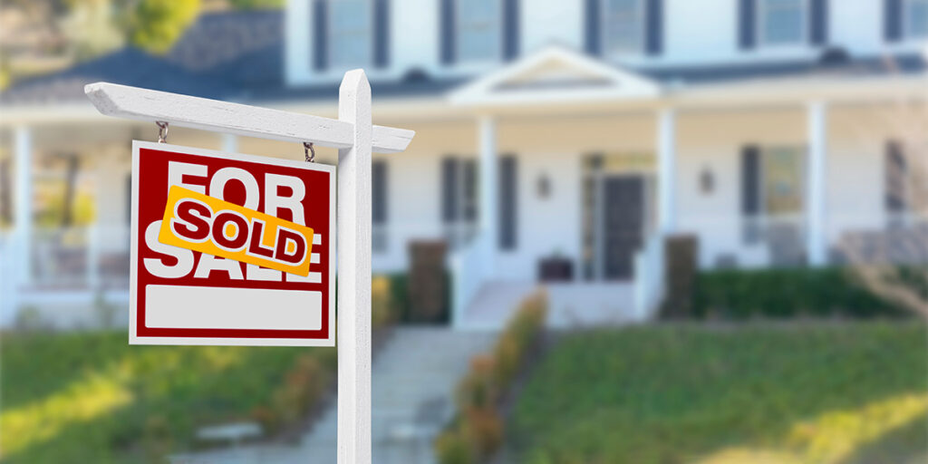 A "sold" sign on the street in front of a house