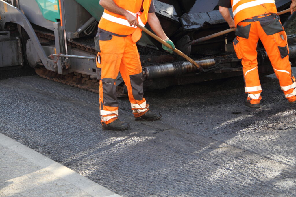 Two workers resurface an asphalt road