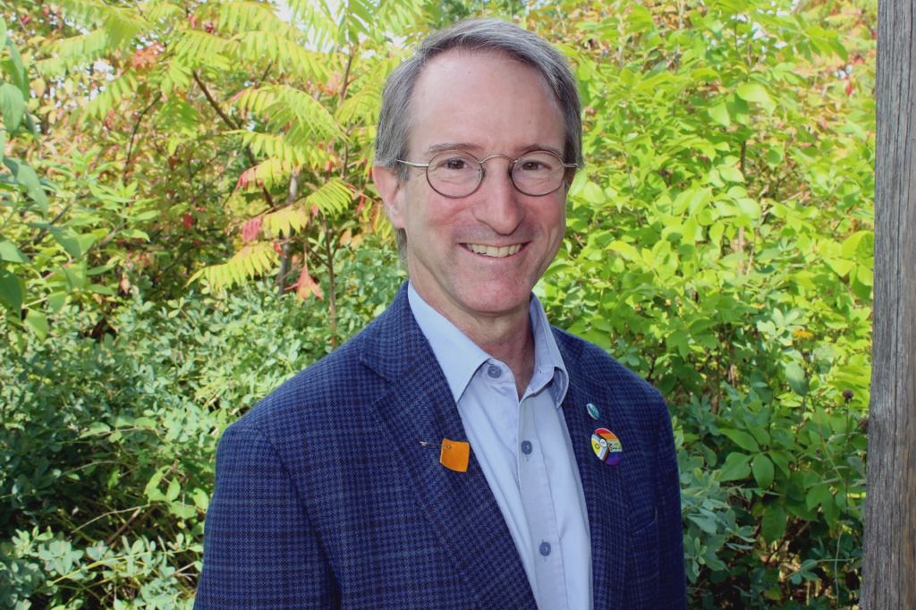 Niagara College Vice-President, Research, Innovation, Strategic Enterprises Dr. Marc Nantel. A smiling bespectacled white man wearing a blue sport coat and blue button-up shirt.