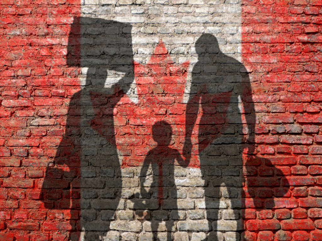 Silhouettes of a family on a wall painted with a Canadian flag