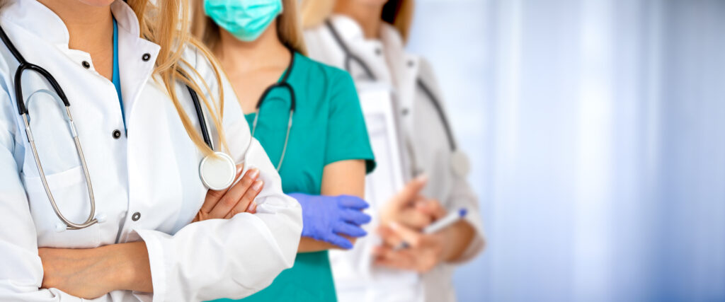 Three doctors stand with their arms folded against a blue background