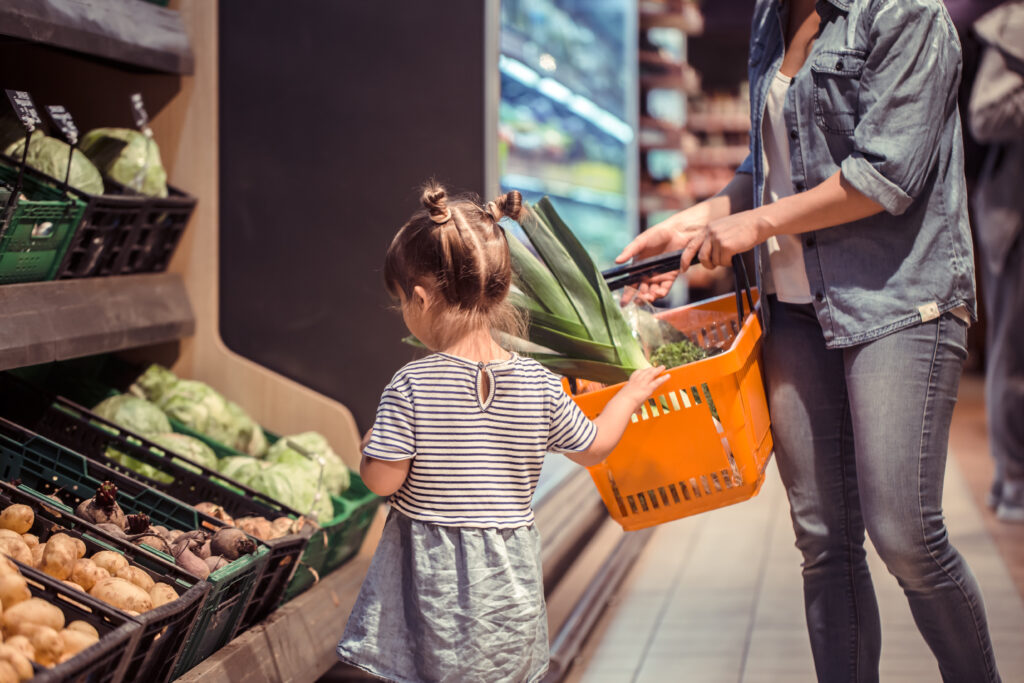 A mother and daughter shop for produce in a grocery store