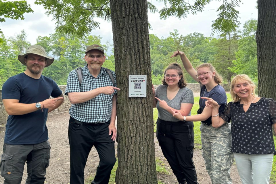 Smiling Niagara Geopark workers and volunteers next to a QR code on a tree