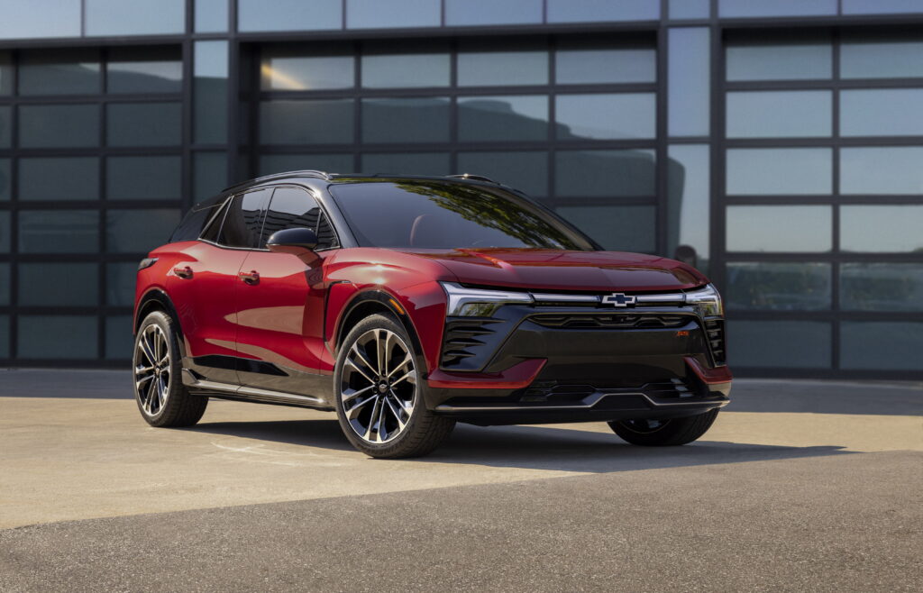 A red 2024 Chevrolet Blazer EV on a forecourt outside a building with mirrored glass walls