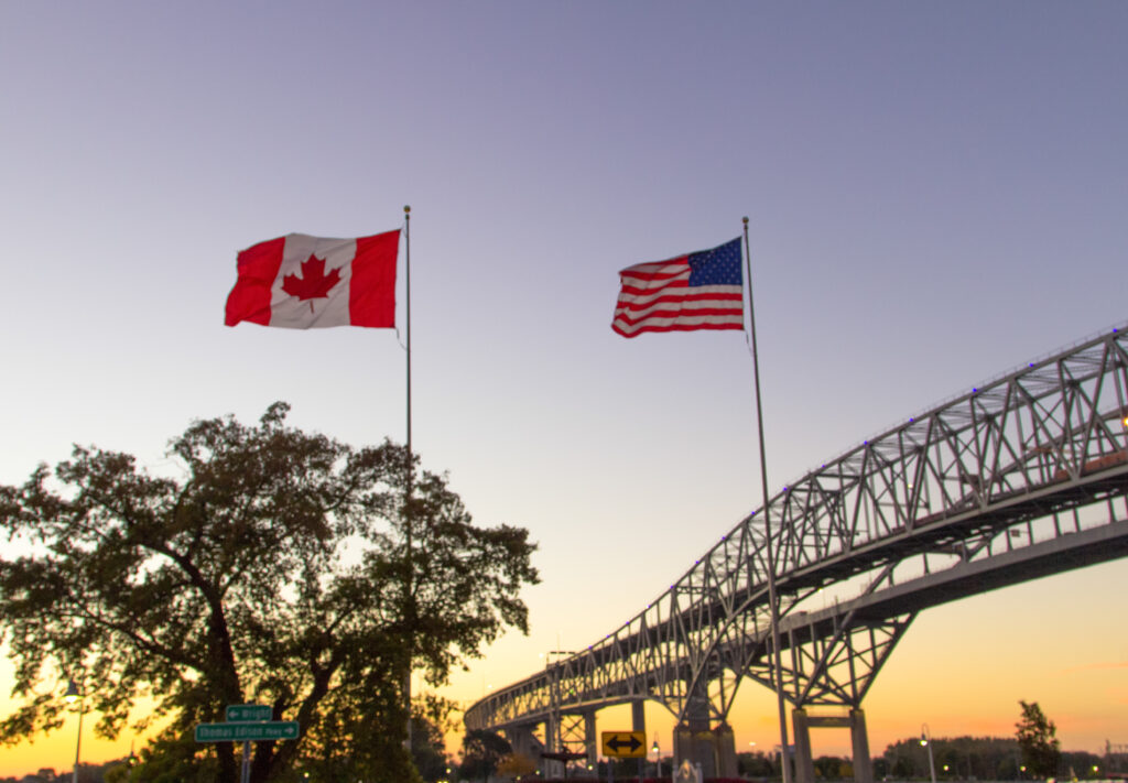 Canadian and U.S. flags flying above the Blue Water Bridge border connecting Port Huron, Michigan and Sarnia, Ontario