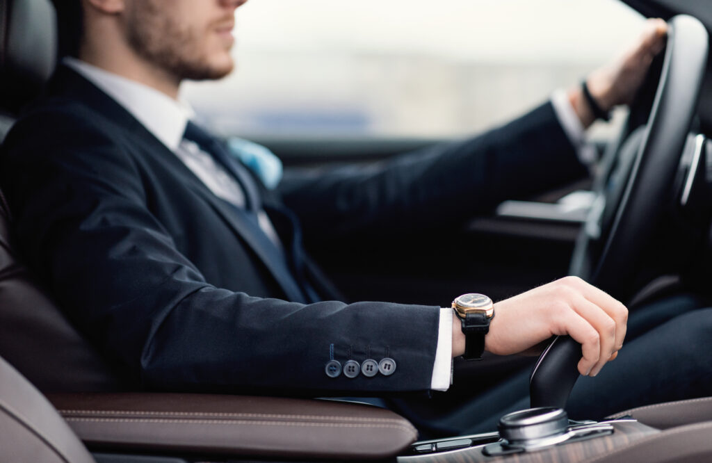 A man wearing a suit driving a car