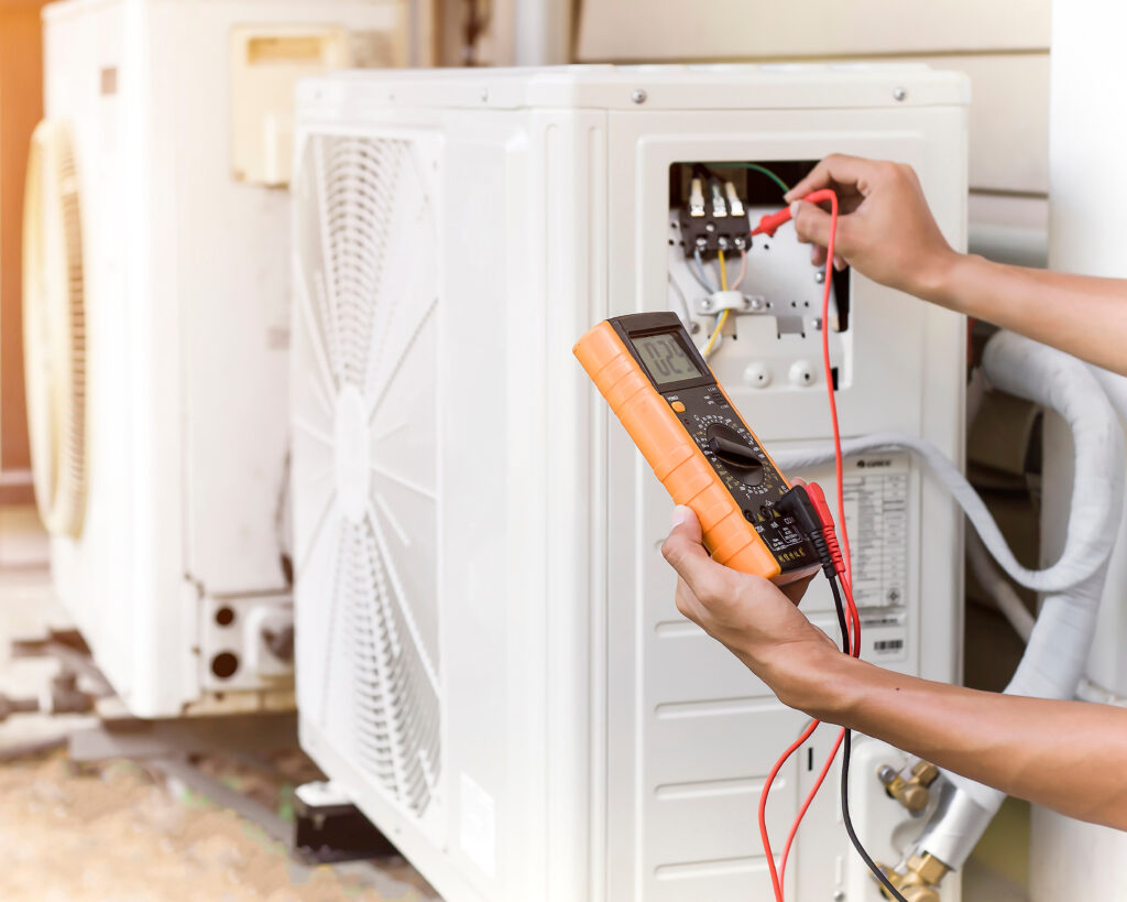 An electrician tests the electrical connections on the external heat exchanger for an air heat pump