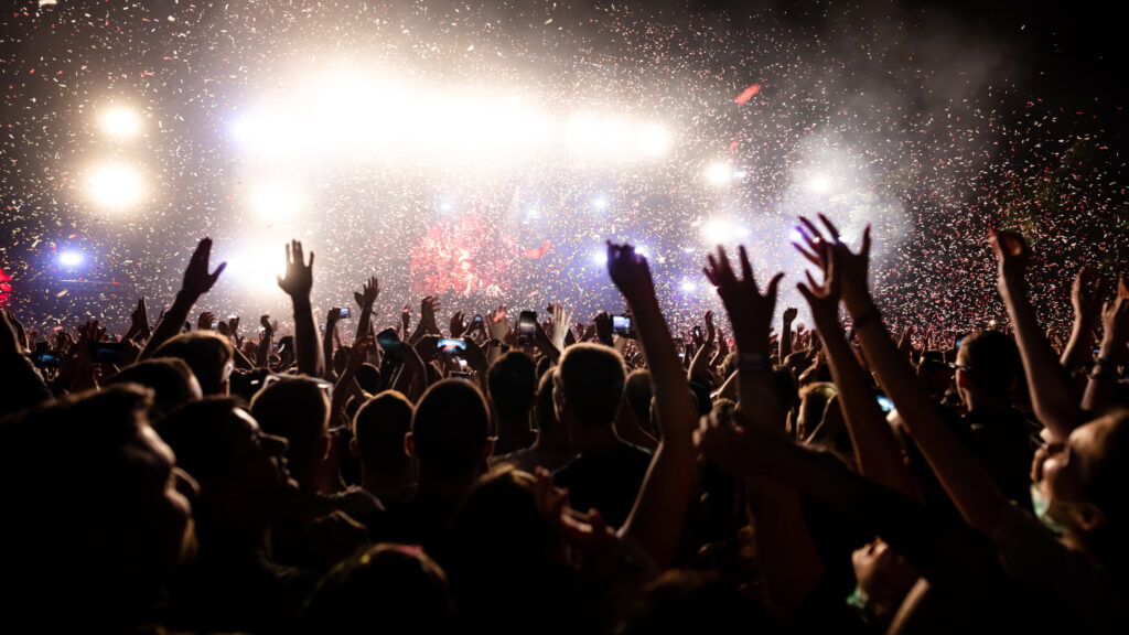 Crowd of people having fun while watching confetti fireworks at music festival.