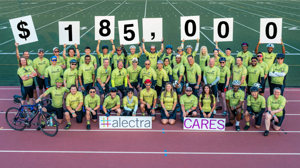 The Alectra Ride to Conquer Cancer team poses for a group photo, holding signs indicating the amount raised